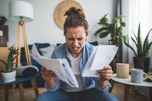 Jeune adulte frustré regardant des factures.