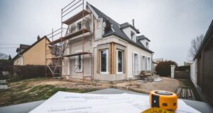 Maison avec extension en travaux et dossiers d’urbanisme sur une table